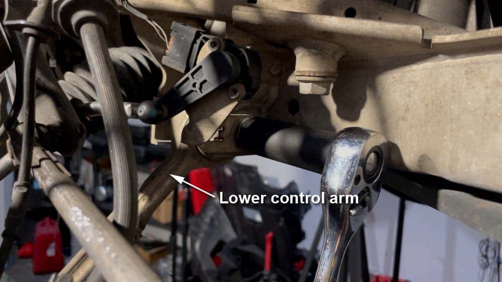 Loosen the nut securing the lower control arm to the frame of the vehicle